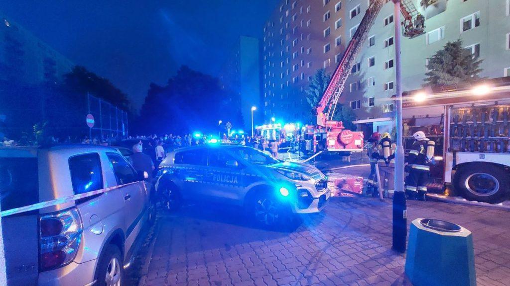 Samochody polici i straży na niebieskich światłach podczas akcji gaśniczej wieżowca