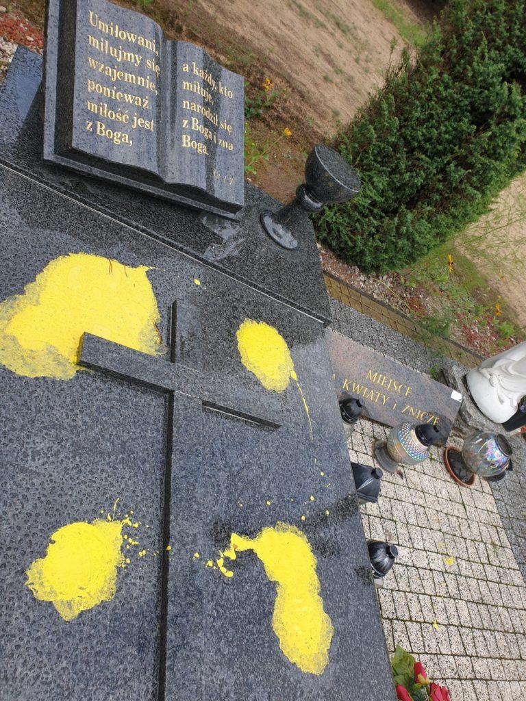 Granitowy nagrobek, na nim żólte plamy farby