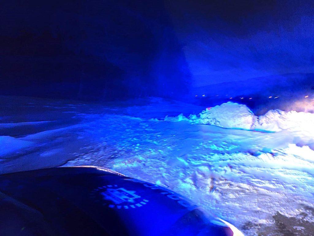 Pole pokryte śniegiem oświetlone reflektorami samochodu