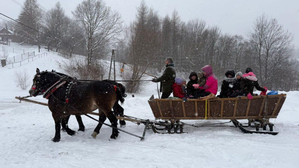 Zimowa zabawa na stoku w Stobiernej – kulig z końmi i uczestnicy wydarzenia OSP Stobierna podczas opadów śniegu