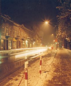 Ulica, noc śnieg na poboczu, po lewej stare kamienice