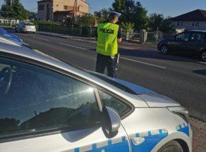 Policjant stoi przy ulicy obok radiowozu