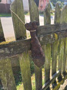 Zardzewiały pocisk moździeżowy wisący na sznurku na płocie