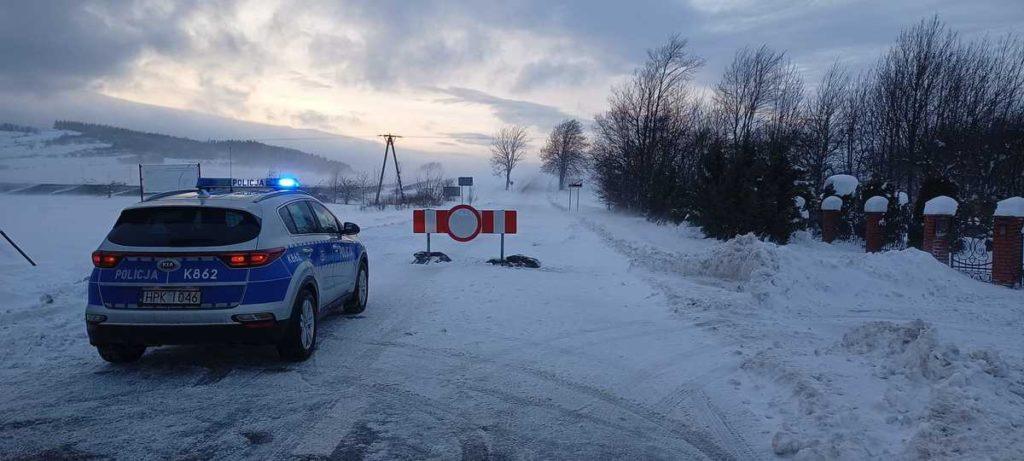 Zasypana droga śniegiem, szlaban na drodze, policyjny radiowóz