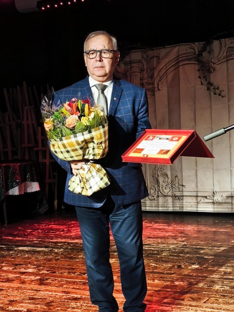 Mężczyzna w garniturze z wiązanką kwiatów i dyplomem