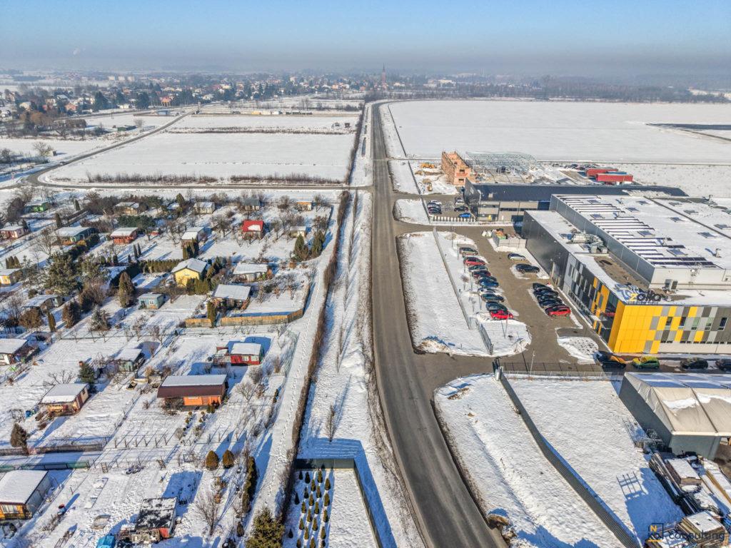 Zaśnieżony krajobraz Podkarpacia z lotu ptaka, droga wojewódzka wiodąca przez teren z budynkami, widok zimowy z góry.