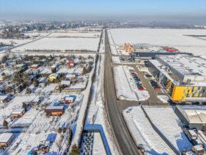 Zaśnieżony krajobraz Podkarpacia z lotu ptaka, droga wojewódzka wiodąca przez teren z budynkami, widok zimowy z góry.