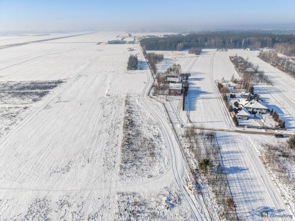 Zaśnieżony krajobraz Podkarpacia z lotu ptaka, droga wojewódzka wiodąca przez teren z budynkami, widok zimowy z góry.