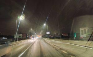 Nocna ulica w powiecie dębickim, delikatnie ośnieżona, przy silnym mrozie. Śnieg opada w świetle latarni i reflektorów miasta, tworząc magiczną, zimową atmosferę.