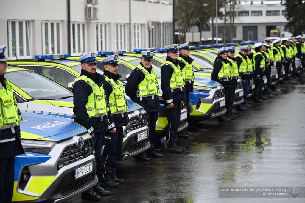 Podkarpacka Policja – funkcjonariusze stojący przed nowoczesnymi radiowozami, w tym SUV i samochodami do przewozu psów służbowyc