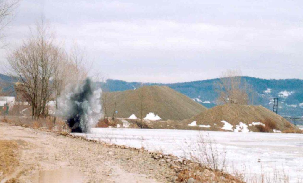 Zima, lód na rzece, wybuch trotylu, czarnoszary dym