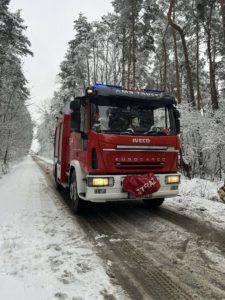 wóz strażacki na zaśnieżonej leśnej drodze