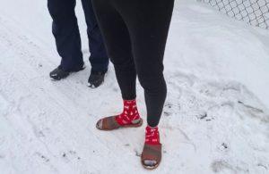 Zatrzymany mężczyzna stoi w skarpetkach i klapkach należących do właściciela domu po interwencji policji.