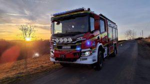 Strażacki samochód gaśniczy podczas akcji gaszenia pożaru suchej trawy na nieużytkach w miejscowości Bukowa.