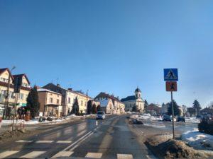 Centrum Brzostka w zimie. Niebieskie niebo, zabytkowa zabudowa i resztki śniegu na poboczach